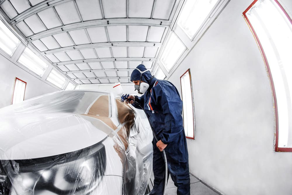 Auto body shop technician painting a car